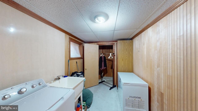 washroom with wood walls, washer / dryer, and crown molding