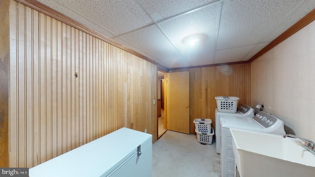 washroom with wood walls, washing machine and dryer, sink, and light carpet