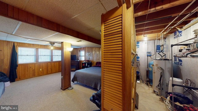 carpeted bedroom with a paneled ceiling, gas water heater, and wooden walls