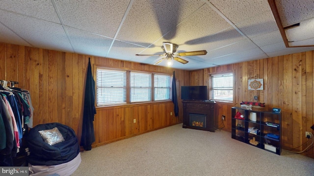 misc room featuring a drop ceiling, ceiling fan, light colored carpet, and wooden walls