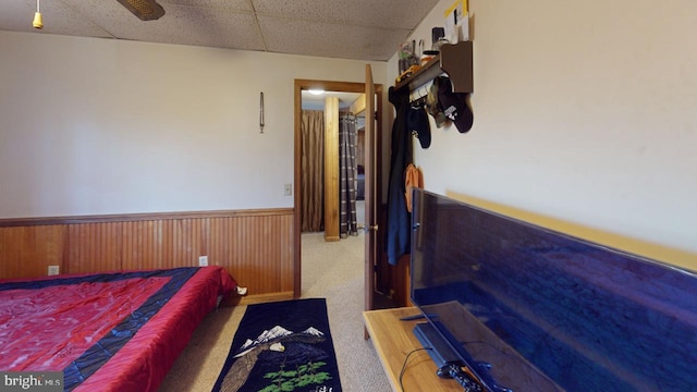 carpeted bedroom with a paneled ceiling and wooden walls