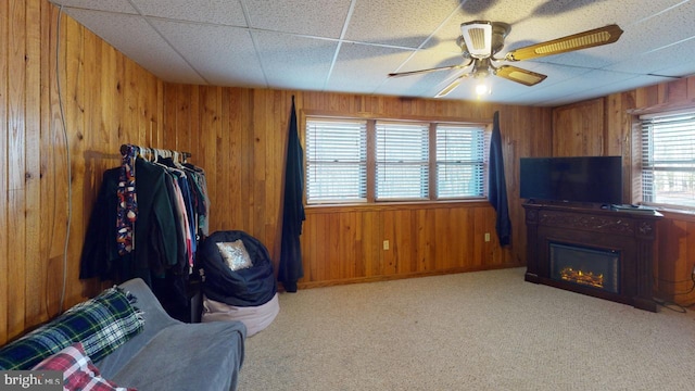 living room with ceiling fan, light colored carpet, and wooden walls