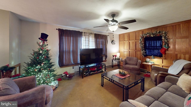 carpeted living room with ceiling fan, a baseboard heating unit, and wood walls