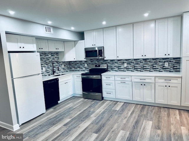 kitchen featuring white cabinetry, sink, stainless steel appliances, backsplash, and light hardwood / wood-style floors