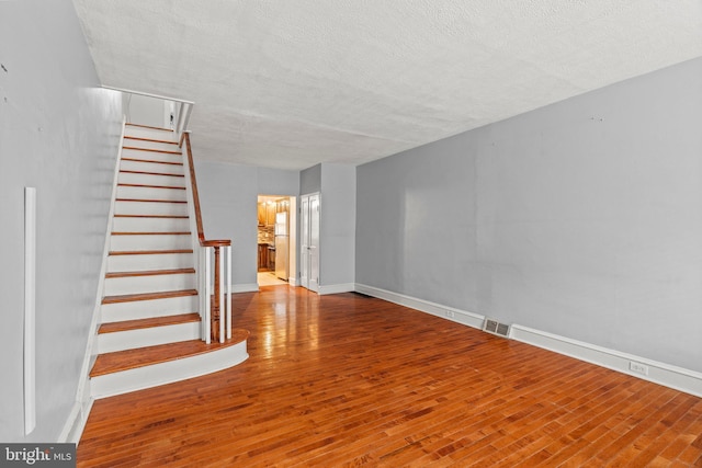 stairs with hardwood / wood-style floors and a textured ceiling