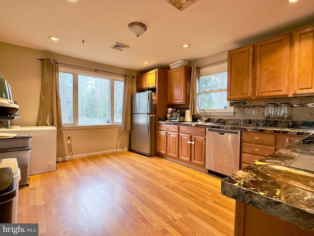 kitchen with backsplash, light hardwood / wood-style floors, sink, and stainless steel appliances