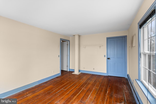 empty room with dark hardwood / wood-style flooring and a baseboard radiator