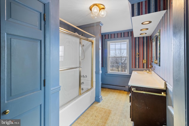 bathroom featuring baseboard heating, vanity, bath / shower combo with glass door, and ornamental molding