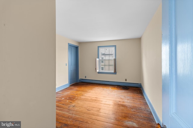 spare room with wood-type flooring and a baseboard heating unit