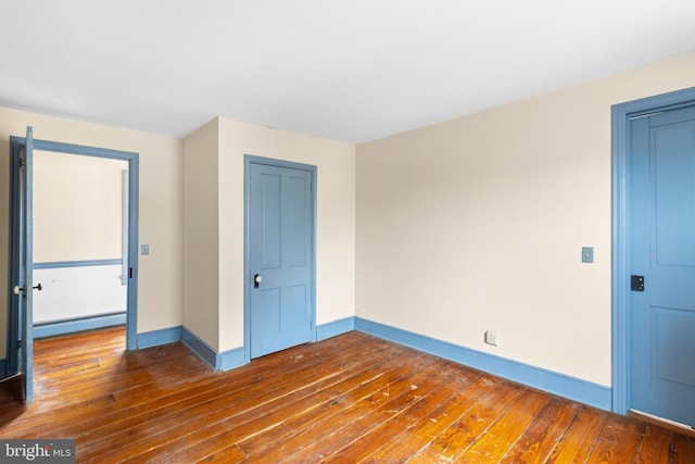 unfurnished room featuring dark hardwood / wood-style floors and a baseboard heating unit