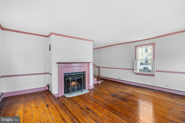 unfurnished living room featuring baseboard heating, dark hardwood / wood-style flooring, and ornamental molding