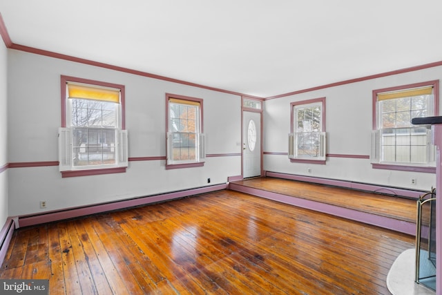 spare room featuring hardwood / wood-style floors, ornamental molding, a wealth of natural light, and a baseboard heating unit