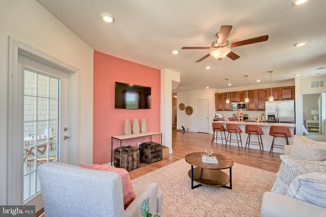 living room featuring ceiling fan, sink, and light hardwood / wood-style floors