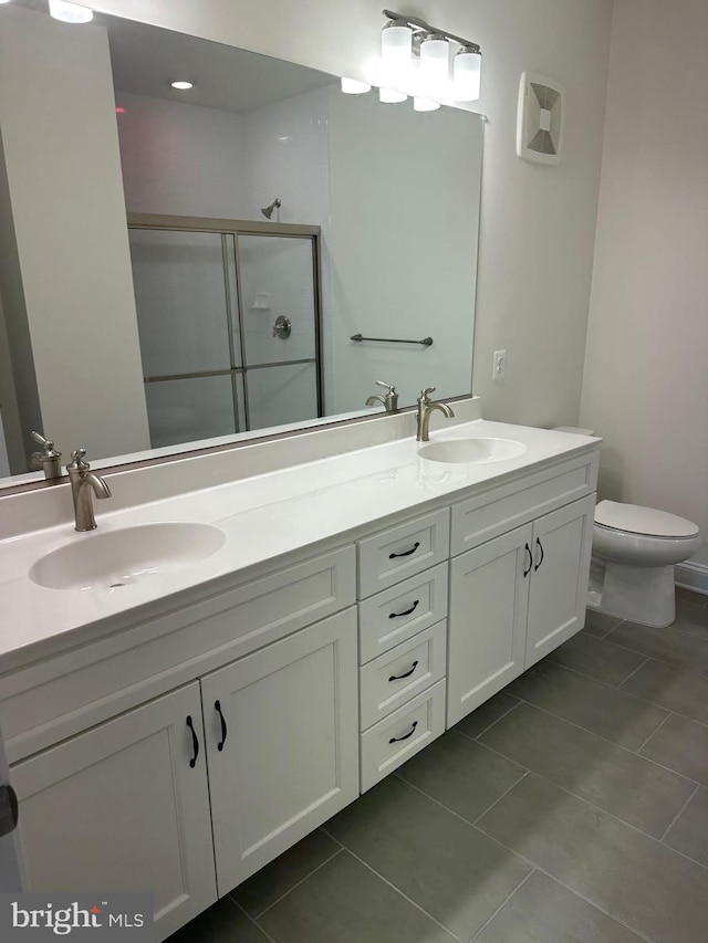 bathroom with tile patterned floors, vanity, toilet, and a shower with shower door