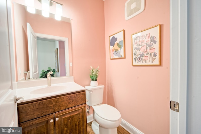 bathroom featuring wood-type flooring, vanity, and toilet