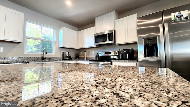kitchen featuring light stone counters, appliances with stainless steel finishes, sink, and white cabinets