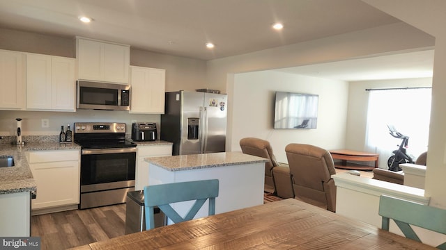 kitchen with light stone countertops, stainless steel appliances, a center island, and white cabinets