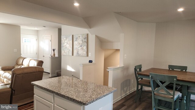 kitchen with light stone countertops, dark hardwood / wood-style floors, and white cabinets