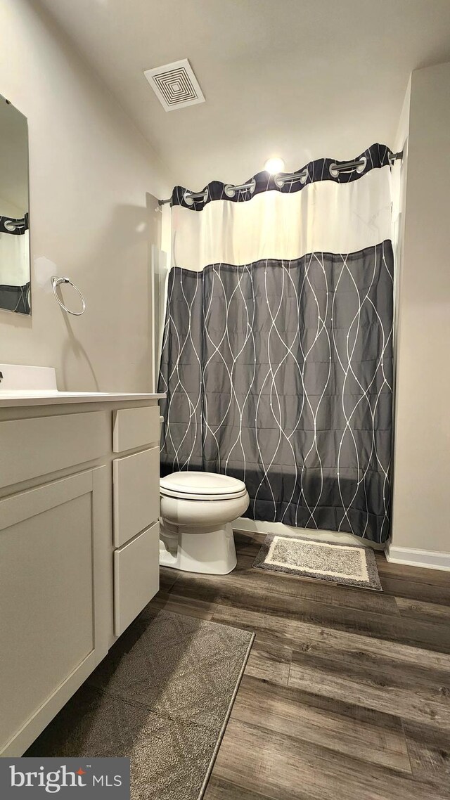 bathroom with vanity, toilet, curtained shower, and hardwood / wood-style floors