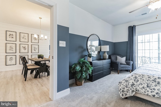 carpeted bedroom with ceiling fan with notable chandelier