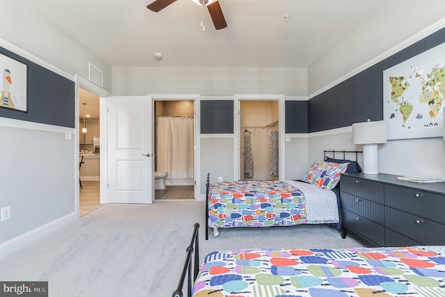 bedroom featuring connected bathroom, a walk in closet, carpet floors, and ceiling fan