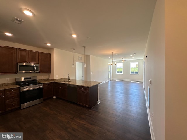 kitchen with sink, appliances with stainless steel finishes, dark hardwood / wood-style floors, decorative light fixtures, and kitchen peninsula