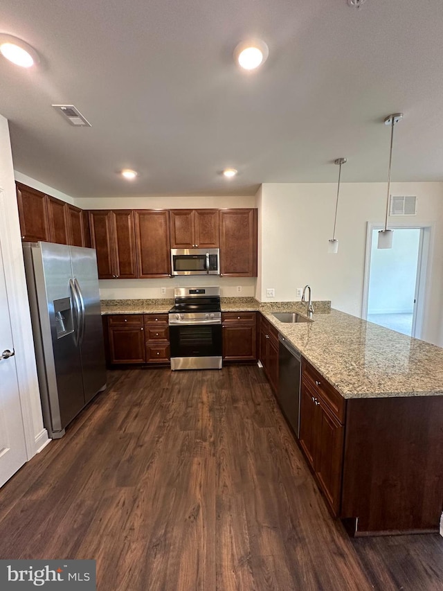 kitchen with decorative light fixtures, sink, kitchen peninsula, stainless steel appliances, and dark wood-type flooring