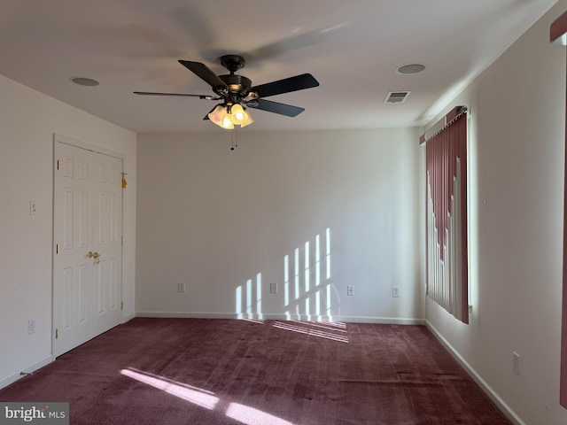 spare room with dark colored carpet and ceiling fan