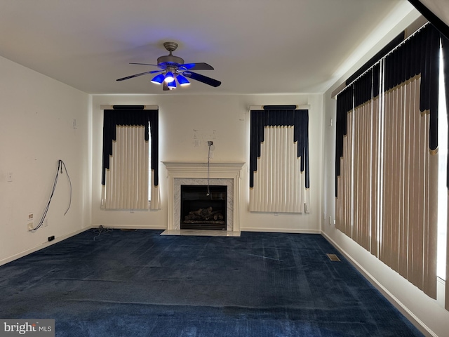 unfurnished living room with ceiling fan and dark carpet