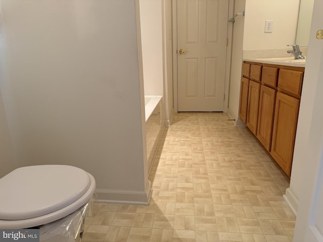 bathroom with a tub to relax in, vanity, and toilet