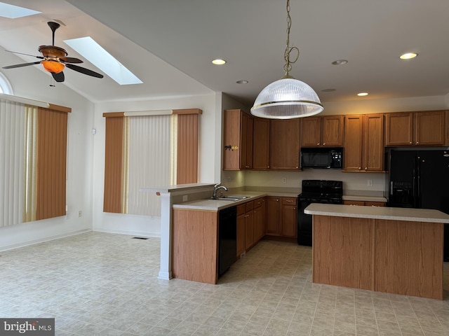 kitchen with vaulted ceiling with skylight, ceiling fan, sink, black appliances, and pendant lighting