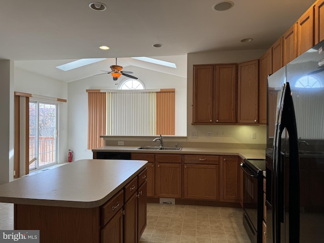 kitchen with vaulted ceiling with skylight, sink, stainless steel fridge with ice dispenser, a kitchen island, and black / electric stove