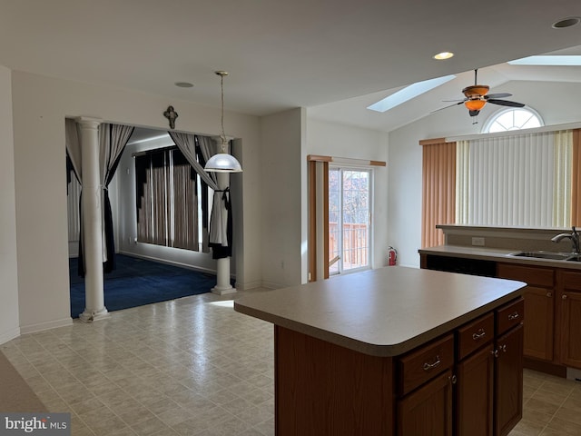 kitchen with vaulted ceiling with skylight, ceiling fan, sink, a center island, and hanging light fixtures