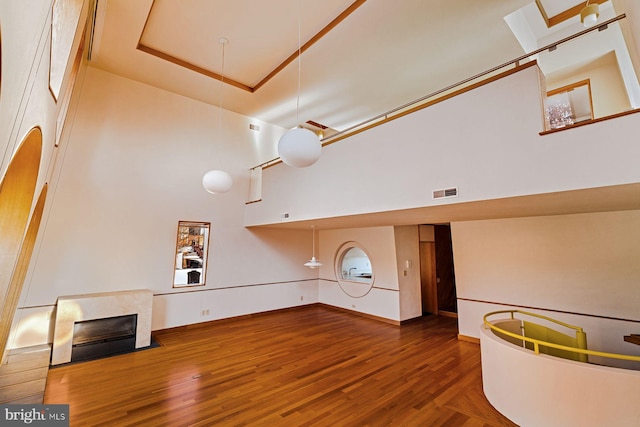 unfurnished living room with hardwood / wood-style floors, a towering ceiling, and a tray ceiling