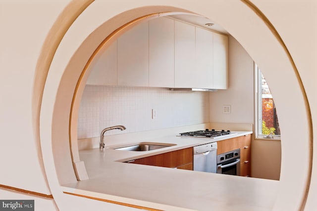 kitchen featuring white cabinets, appliances with stainless steel finishes, decorative backsplash, and sink