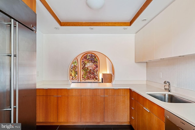 kitchen featuring backsplash, stainless steel appliances, a raised ceiling, and sink