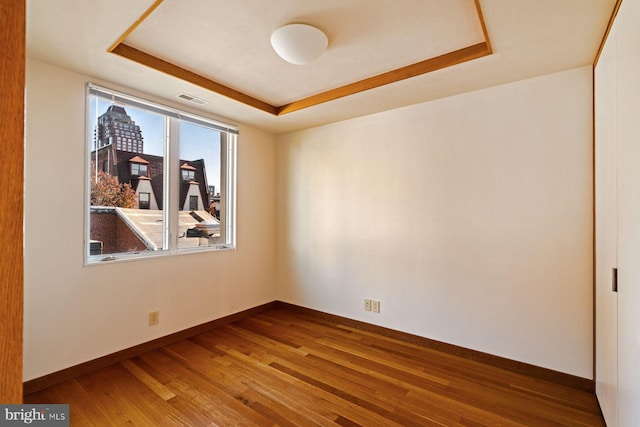 unfurnished room featuring hardwood / wood-style flooring and a tray ceiling