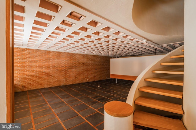 additional living space with dark tile patterned floors and brick wall