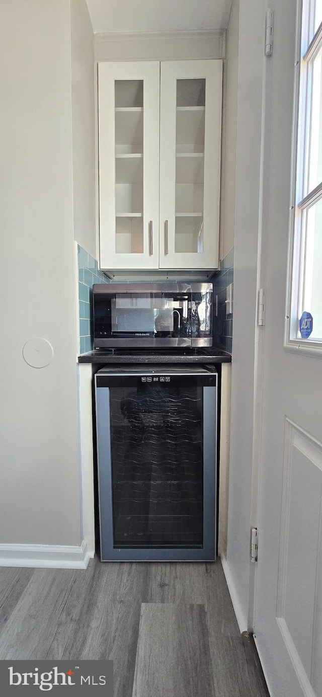 interior space featuring decorative backsplash, white cabinetry, wine cooler, and hardwood / wood-style flooring