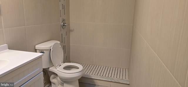 bathroom with walk in shower, vanity, tile walls, and toilet