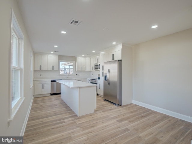 kitchen featuring white cabinetry, sink, stainless steel appliances, light hardwood / wood-style flooring, and a kitchen island