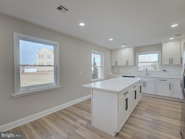 kitchen featuring light wood-type flooring, white cabinetry, sink, and tasteful backsplash