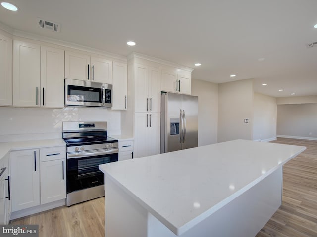 kitchen with a center island, white cabinets, stainless steel appliances, and light wood-type flooring