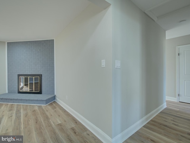 additional living space with a brick fireplace and light wood-type flooring