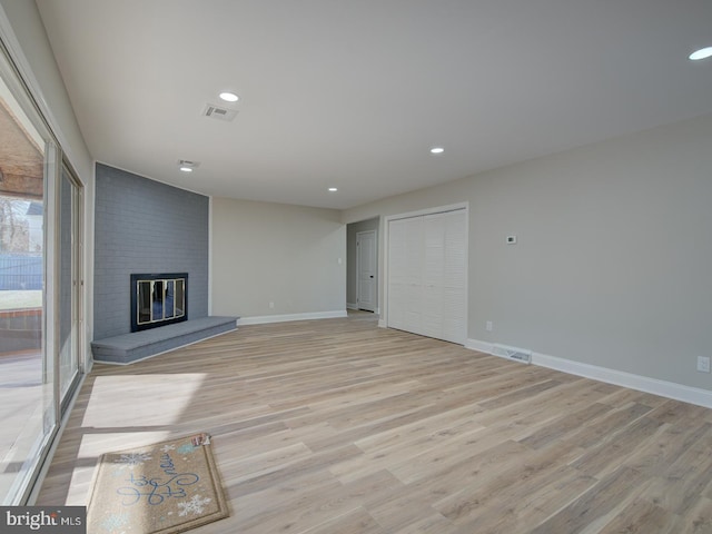 unfurnished living room with a brick fireplace and light wood-type flooring