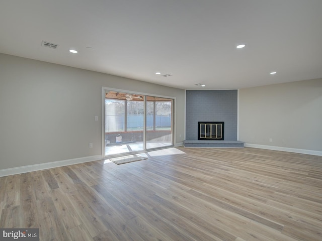 unfurnished living room with light hardwood / wood-style floors and a brick fireplace