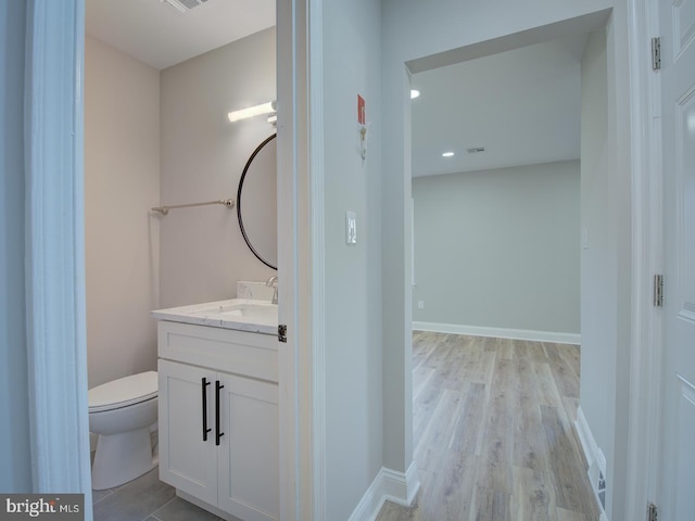 bathroom featuring wood-type flooring, vanity, and toilet