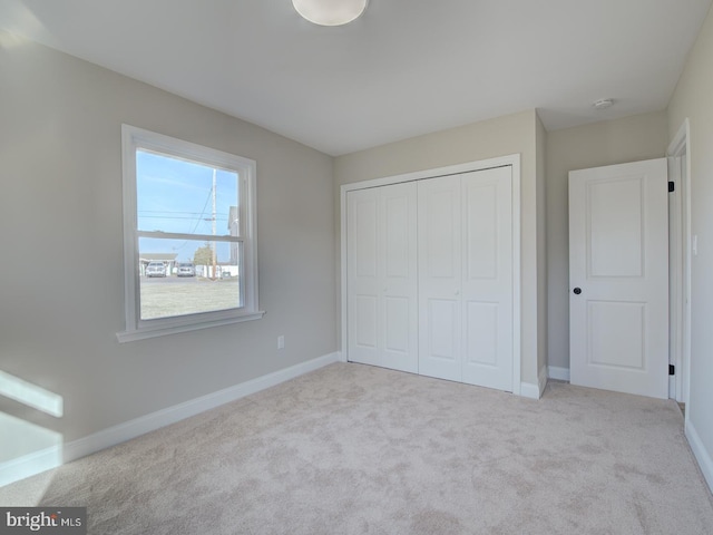 unfurnished bedroom featuring light carpet and a closet