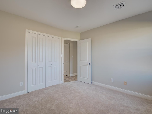 unfurnished bedroom with light carpet and a closet