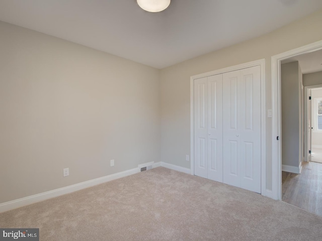 unfurnished bedroom featuring light carpet and a closet